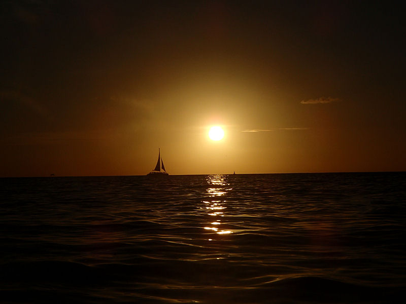 Sailboat passing the setting sun